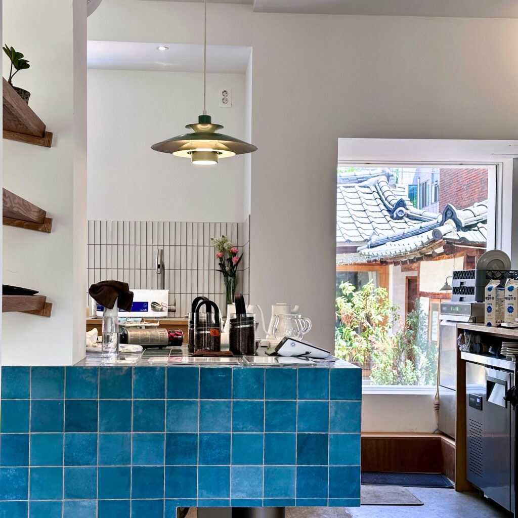 Blue tiled counter with a green pendant lamp and a window view of hanok rooftops