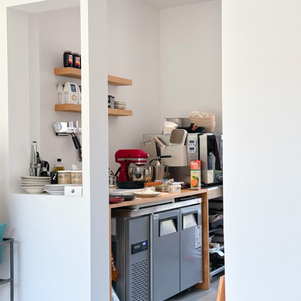 Open kitchen with a red stand mixer, wooden shelves, and baking supplies