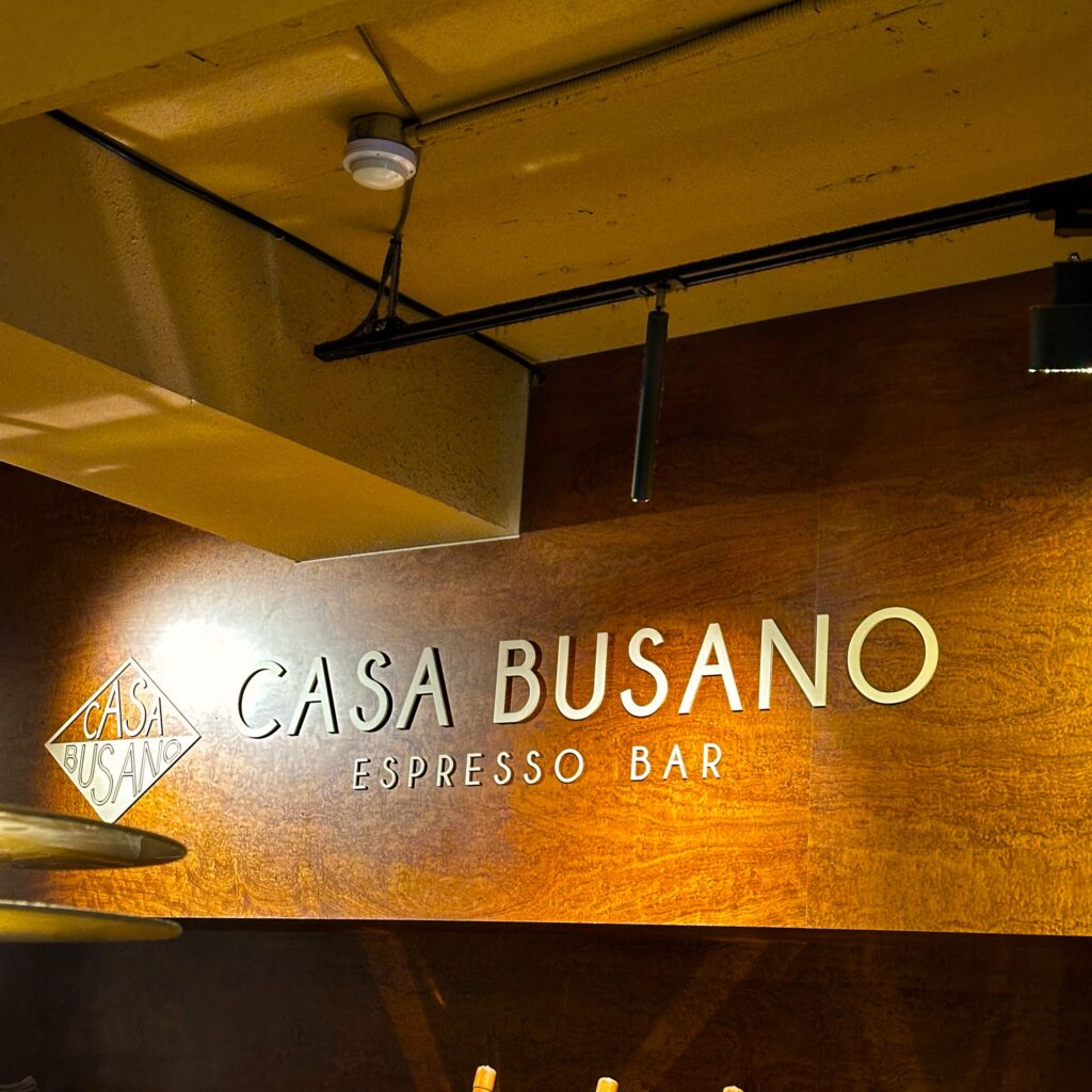 CASA BUSANO ESPRESSO BAR lettering on a warm wood-paneled wall