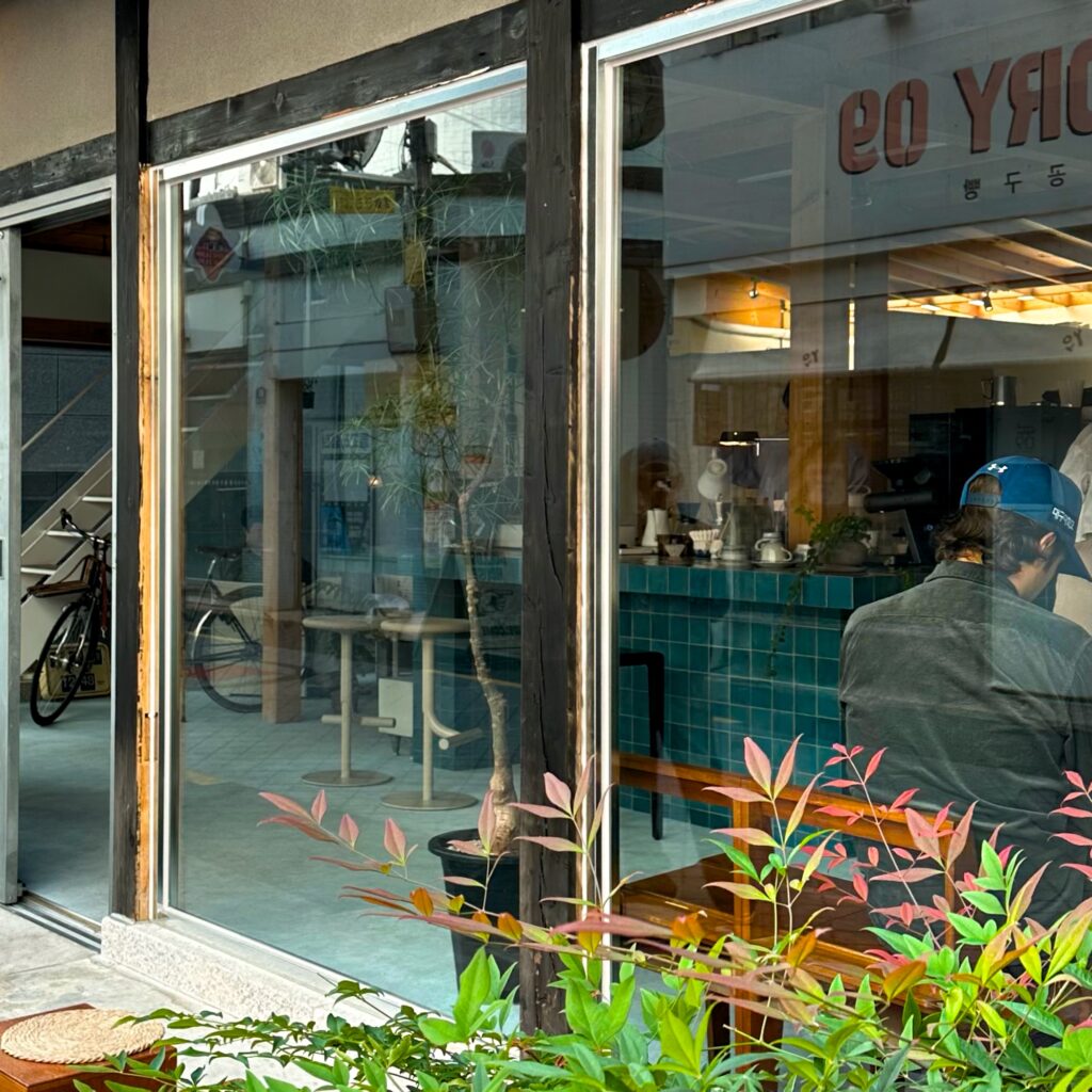 Large glass windows with red-tinged leaves in the planter outside and a blue tiled counter inside