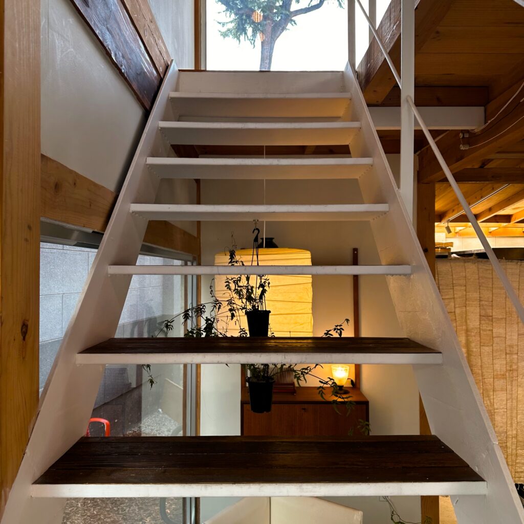 Looking up the white open staircase toward the second floor and its wooden beams