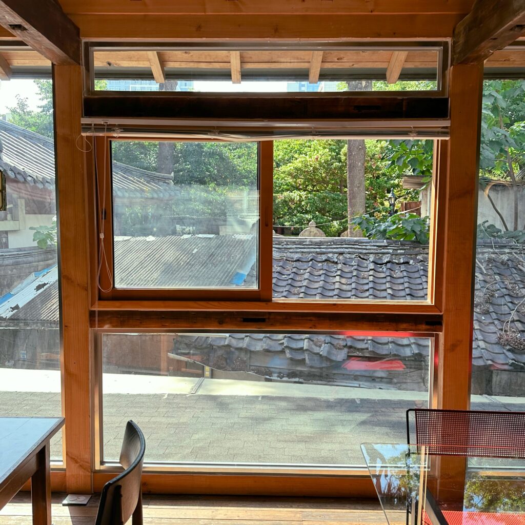 Wooden-framed windows looking out over tiled rooftops and green trees